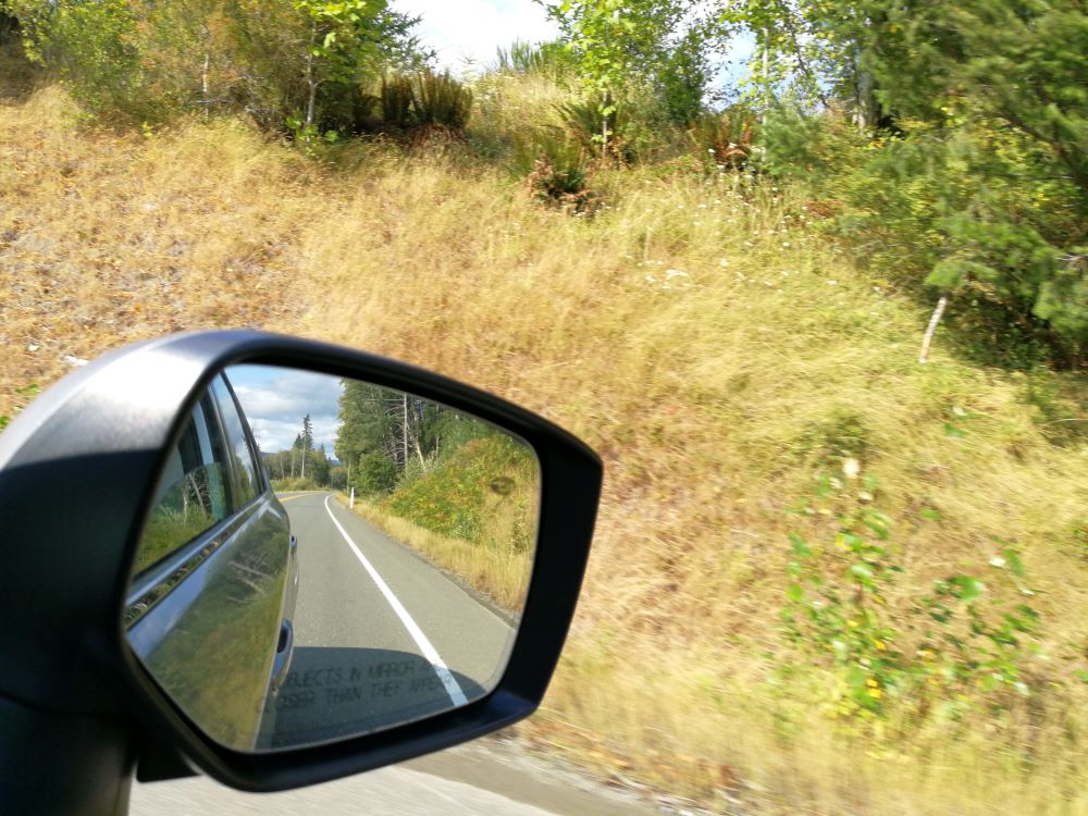 roadside photo taken from the rear mirror, reflecting the winding highway