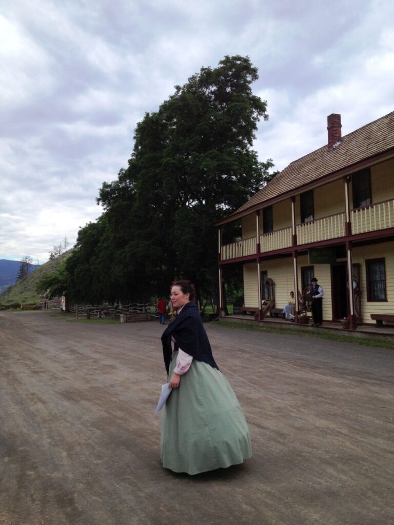 A lady in historic costume standing in front of the Historic Hat Creek Ranch's hotel building